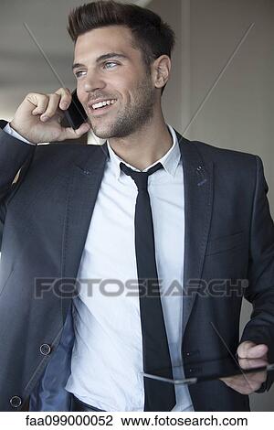 Stock Image - Young businessman taking phone call on the move. Fotosearch