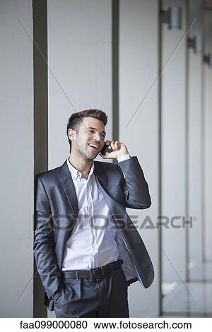 Young man leaning against buiding column talking on cell phone View Large Photo Image Stock Image - Young man leaning against buiding column talking on cell phone. Fotosearch