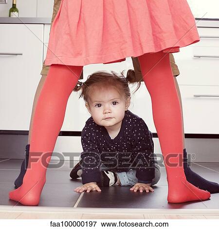 Stock Photo - Baby girl crawling through siblings' legs. Fotosearch
