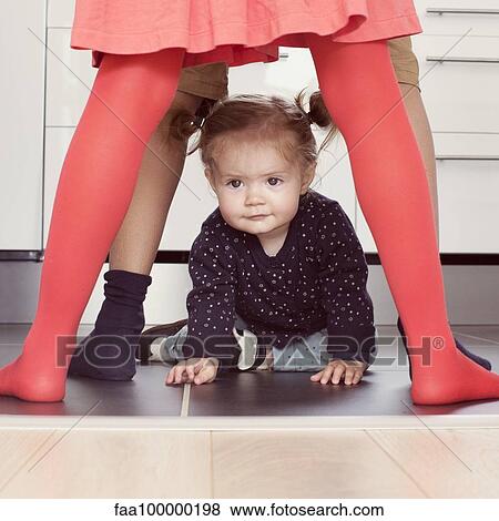 Stock Photo - Baby girl crawling through siblings' legs. Fotosearch