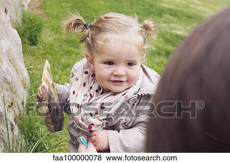 Baby girl outdoors, bag of snacks in hand View Large Photo Image Stock Photo - Baby girl outdoors, bag of snacks in hand. Fotosearch