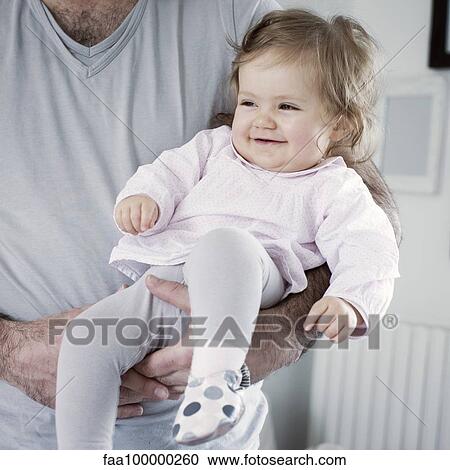 Stock Image - Baby girl resting in father's arms, smiling. Fotosearch