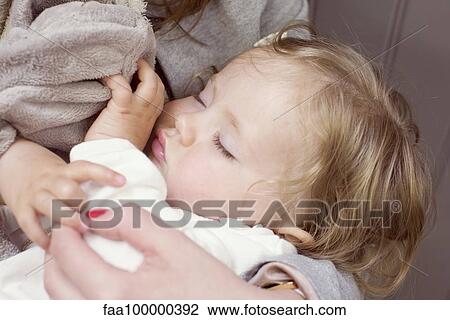 Stock Image - Baby girl sleeping in mother's arms, cropped. Fotosearch