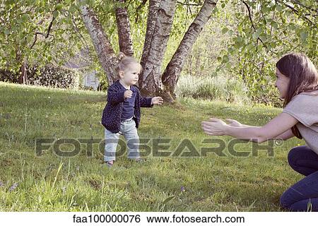 Baby girl taking her first steps outdoors View Large Photo Image Stock Photograph - Baby girl taking her first steps outdoors. Fotosearch