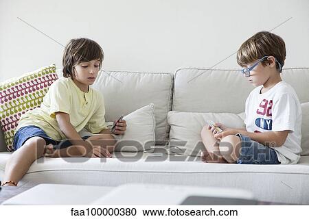 Boys sitting on sofa playing cards View Large Photo Image Stock Image - Boys sitting on sofa playing cards. Fotosearch