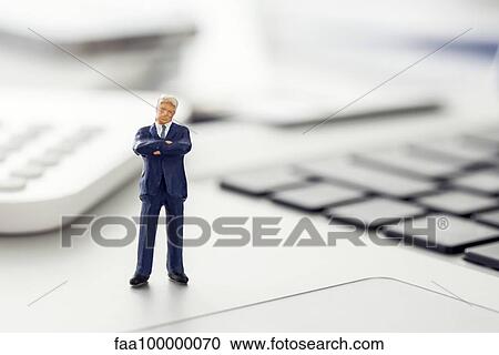 Stock Image - Businessman figurine standing on laptop computer keyboard. Fotosearch