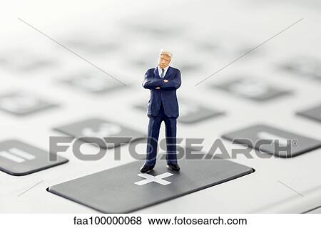 Businessman figurine standing on calculator View Large Photo Image Stock Photo - Businessman figurine standing on calculator. Fotosearch