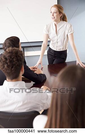 Stock Image - Businesswoman facilitating group discussion at business meeting. Fotosearch