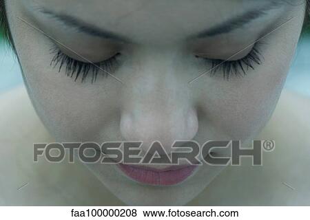 Stock Photo - Close-up of young woman's face, eyes closed. Fotosearch