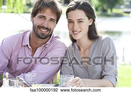 Stock Image - Couple enjoying picnic with family. Fotosearch