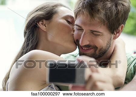 Couple kissing and taking selfie View Large Photo Image Stock Photo - Couple kissing and taking selfie. Fotosearch