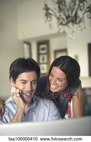 Couple looking at laptop computer smiling View Large Photo Image Stock Image - Couple looking at laptop computer smiling. Fotosearch