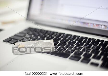 Stock Image - Credit card resting on laptop computer. Fotosearch