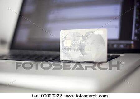 Stock Image - Credit card resting on laptop computer. Fotosearch