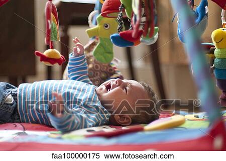 Stock Photography - Crying baby lying on back under mobile. Fotosearch