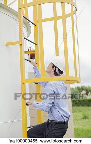 Engineer climbing storage tank ladder at industrial site View Large Photo Image Stock Photography - Engineer climbing storage tank ladder at industrial site. Fotosearch