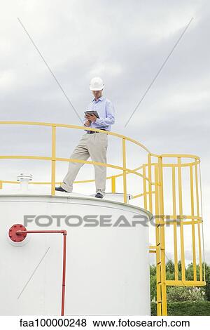 Stock Photo - Engineer inspecting chemical storage tank. Fotosearch