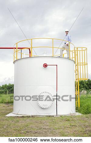Stock Photograph - Engineer inspecting chemical storage tank. Fotosearch