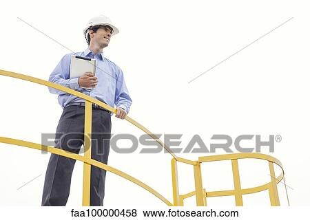 Engineer inspecting industrial site, low angle view View Large Photo Image Stock Photo - Engineer inspecting industrial site, low angle view. Fotosearch