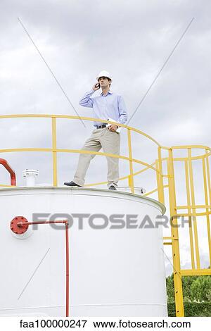 Stock Photo - Engineer inspecting industrial storage tank. Fotosearch
