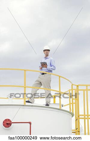 Stock Photo - Engineer inspecting industrial storage tank. Fotosearch