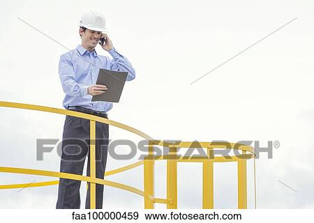 Stock Photo - Engineer overseeing oil refinery production. Fotosearch