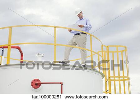 Engineer reviewing plans at industrial plant View Large Photo Image Stock Image - Engineer reviewing plans at industrial plant. Fotosearch