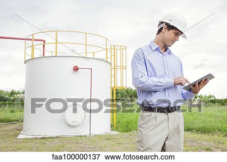 Engineer using digital tablet at industrial chemical storage site View Large Photo Image Stock Photo - Engineer using digital tablet at industrial chemical storage site. Fotosearch