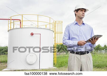 Engineer using digital tablet at industrial chemical storage site View Large Photo Image Stock Photo - Engineer using digital tablet at industrial chemical storage site. Fotosearch