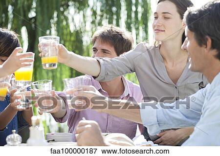 Stock Photo - Family clinking glasses at outdoor gathering. Fotosearch