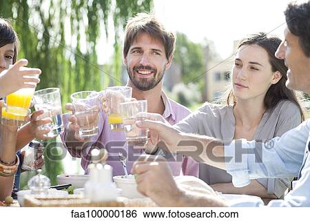 Stock Photograph - Family clinking glasses at outdoor gathering. Fotosearch