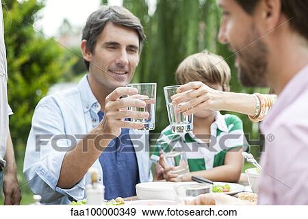 Stock Photo - Family clinking glasses outdoors. Fotosearch
