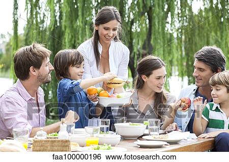 Stock Photograph - Family eating healthy meal together outdoors. Fotosearch