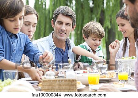 Family eating together at outdoor gathering View Large Photo Image Picture - Family eating together at outdoor gathering. Fotosearch