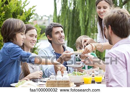 Family eating together at outdoor gathering View Large Photo Image Stock Image - Family eating together at outdoor gathering. Fotosearch