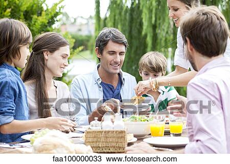 Family eating together at outdoor gathering View Large Photo Image Stock Image - Family eating together at outdoor gathering. Fotosearch