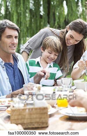 Family eating together at outdoor gathering View Large Photo Image Stock Image - Family eating together at outdoor gathering. Fotosearch