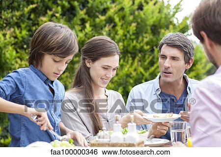Stock Photograph - Family eating together at outdoor gathering. Fotosearch