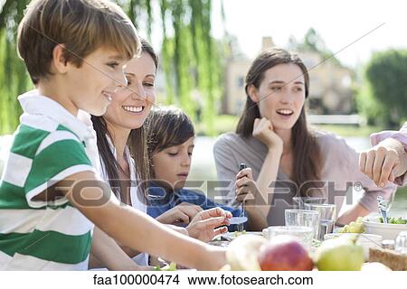 Family eating together outdoors View Large Photo Image Picture - Family eating together outdoors. Fotosearch