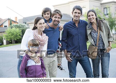 Stock Image - Family posing together on suburban street, portrait. Fotosearch