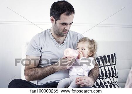 Father holding baby girl on lap, feeding her with bottle View Large Photo Image Stock Photography - Father holding baby girl on lap, feeding her with bottle. Fotosearch