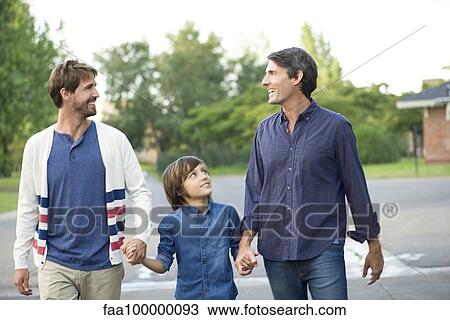 Stock Image - Fathers holding hands with son outdoors. Fotosearch