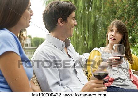 Friends relaxing outdoors with glass of wine View Large Photo Image Stock Image - Friends relaxing outdoors with glass of wine. Fotosearch