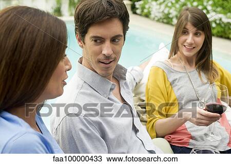 Friends relaxing together by pool with glass of wine View Large Photo Image Stock Image - Friends relaxing together by pool with glass of wine. Fotosearch