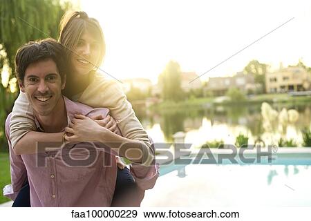 Stock Photo - Man giving girlfriend piggyback ride, portrait. Fotosearch