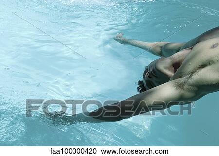 Stock Image - Man leaning backward over swimming pool, dangling arms in water. Fotosearch