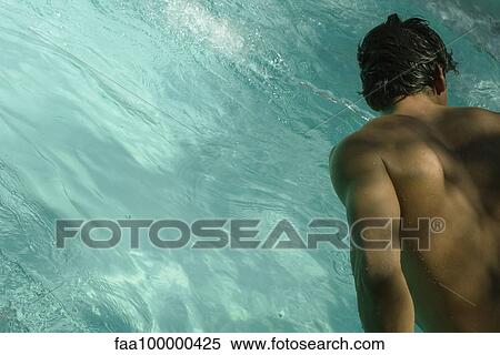 Stock Photography - Man leaning over pool, rear view. Fotosearch