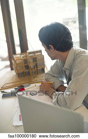 Man sitting at desk, looking out of window View Large Photo Image Stock Image - Man sitting at desk, looking out of window. Fotosearch