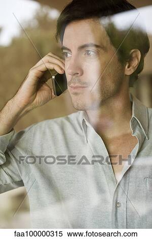 Stock Photography - Man using cell phone looking out window. Fotosearch