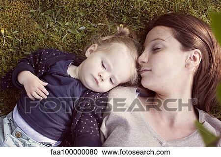 Stock Image - Mother and baby girl napping on grass. Fotosearch